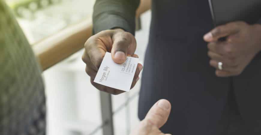 Close up of a businessman handing another man his business card.