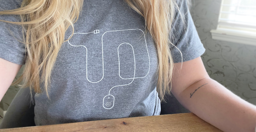 Close up of female wearing heather gray 10-year anniversary shirt while sitting at desk.